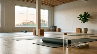 A bright, airy yoga studio at sunrise with a folded mat and a water bottle